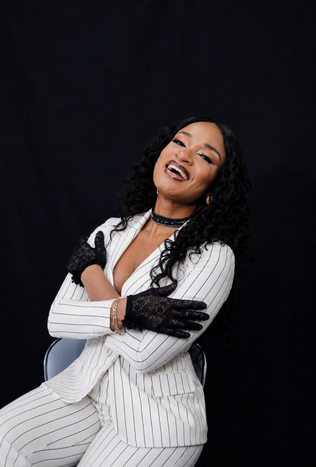 Tunde Girl seated in a white pinstripe suit